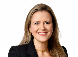 Emma Hilliard, a woman with long brown hair, wearing a black top and a pearl necklace, poses against a plain white background.
