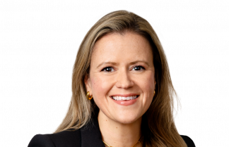Emma Hilliard, a woman with long brown hair, wearing a black top and a pearl necklace, poses against a plain white background.